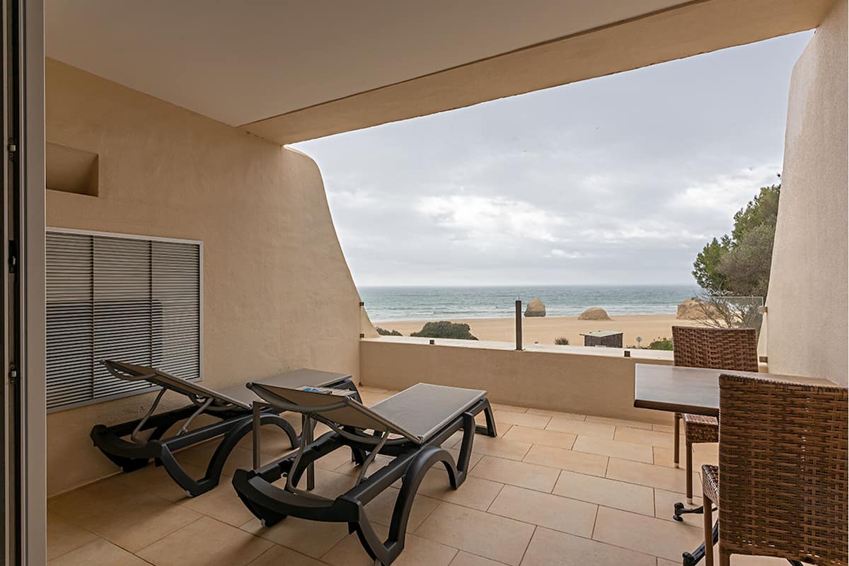 Ein Balkon mit Blick auf den Strand, inklusive Tisch, zwei Stühlen und einem Laufband.