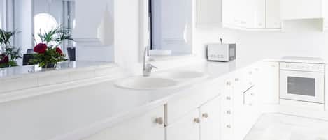 Een moderne, witte badkamer met een grote spiegel, twee wastafels, een toilet en een douche.