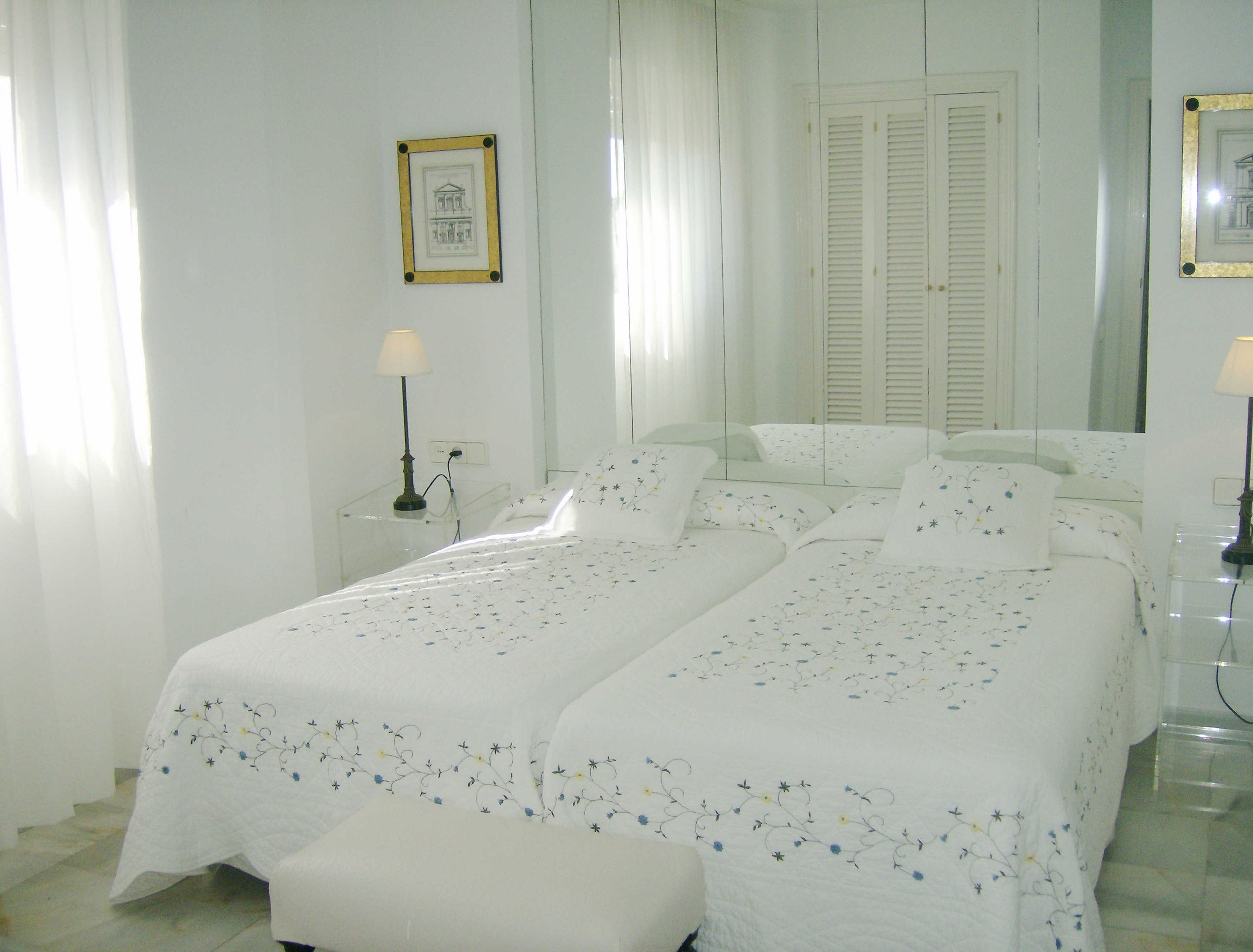 Un dormitorio con dos camas, una mesita de noche, una lámpara y un cuadro enmarcado en la pared.
