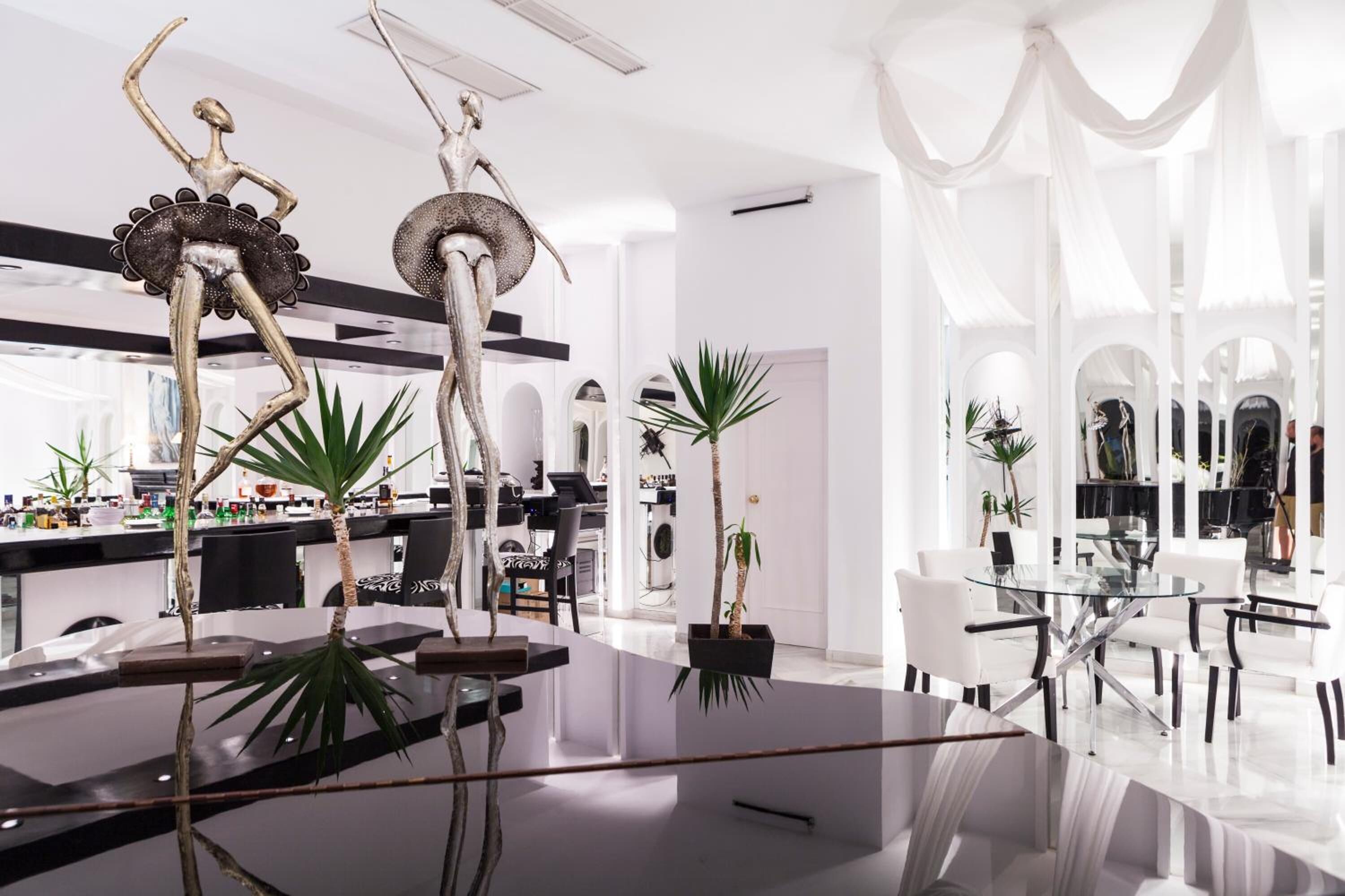 A modern interior with a central glass table, white walls, and minimalist decor.
