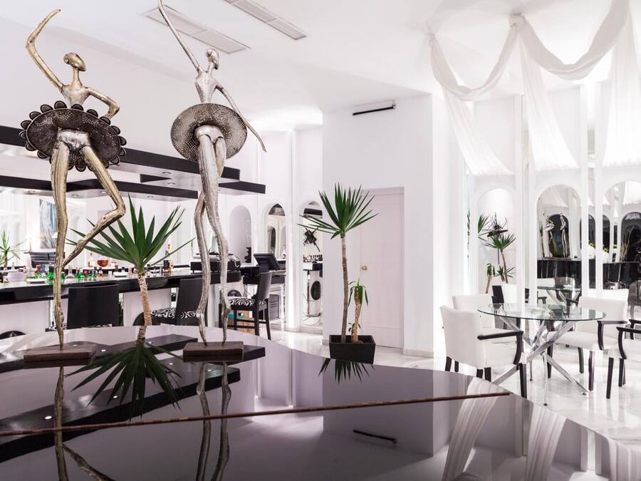 A modern interior with a central glass table, white walls, and minimalist decor.