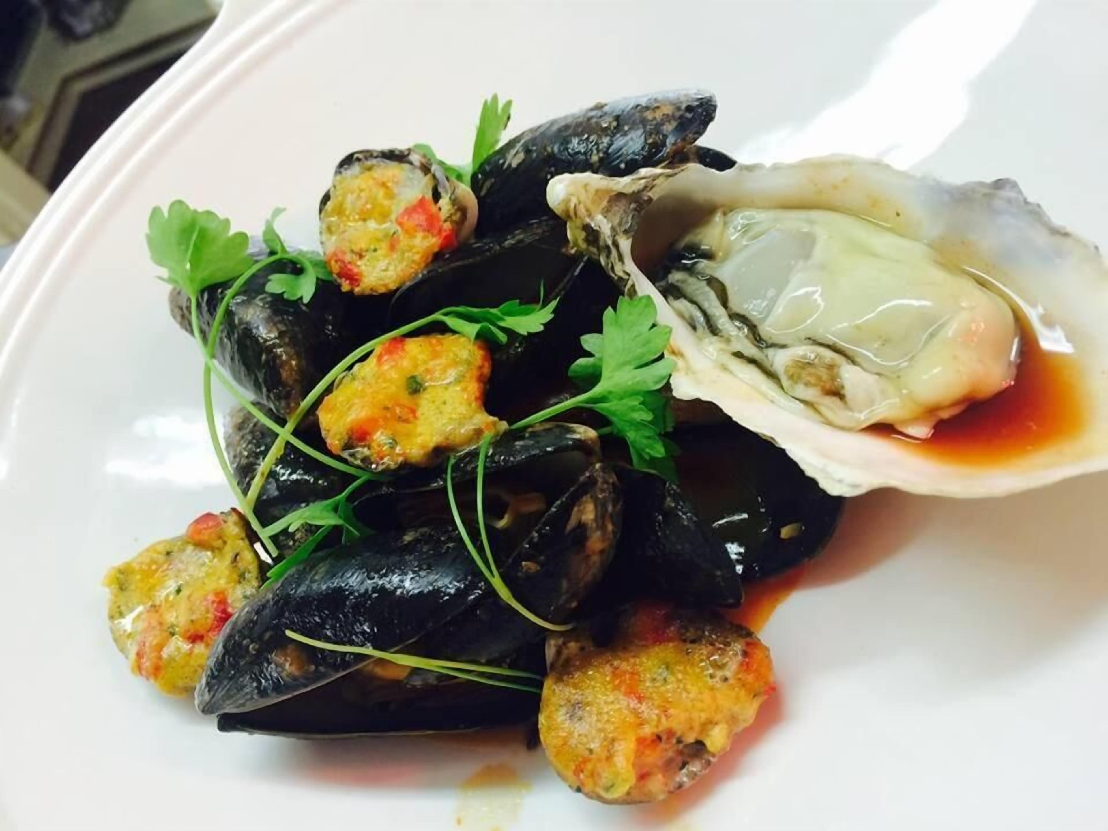 Mussels and an oyster on a plate.