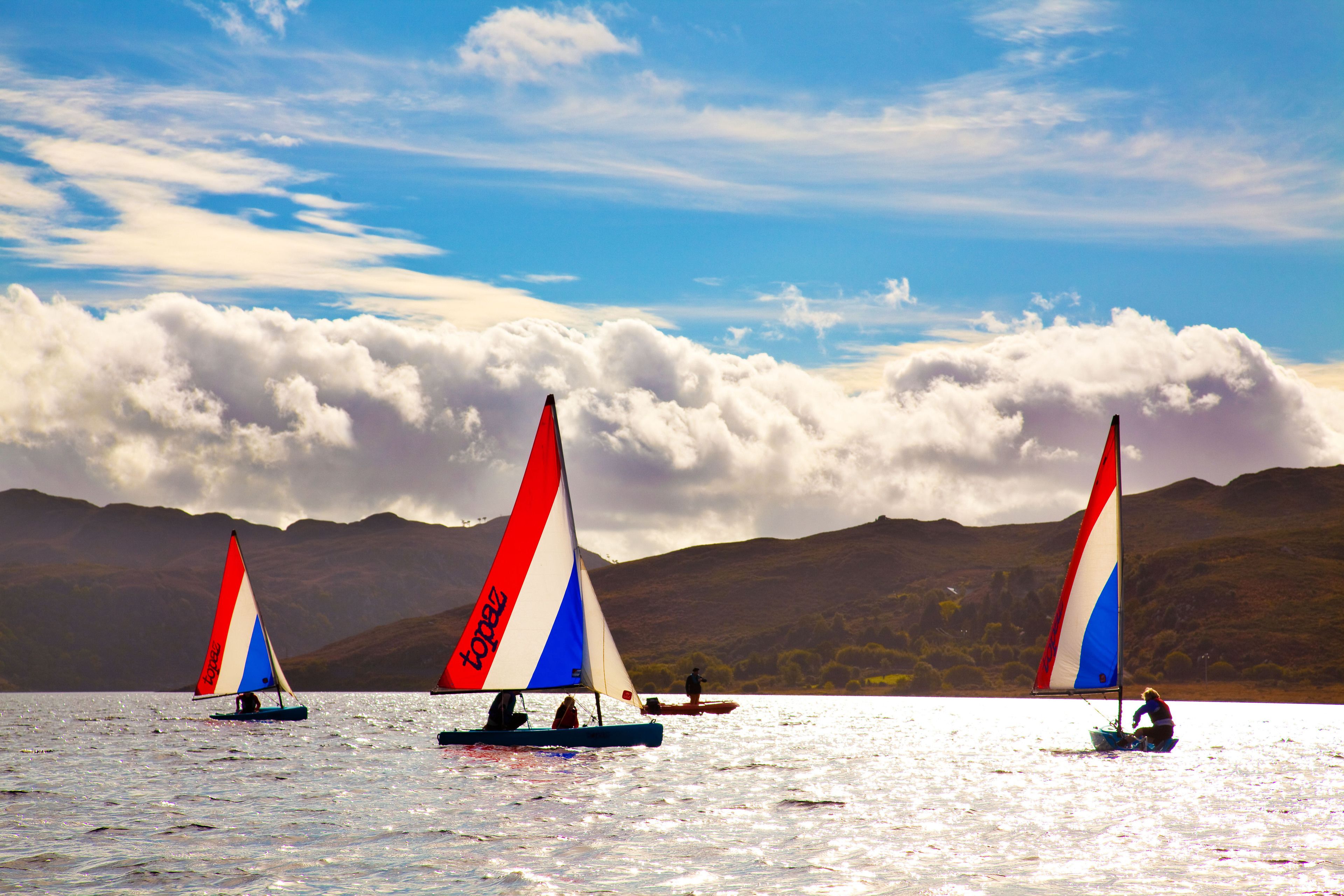Tres veleros en un lago con montañas al fondo.