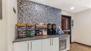 Zona de recepció d'hotel amb un espai per al cafè, un refrigerador i una porta amb el número 1.