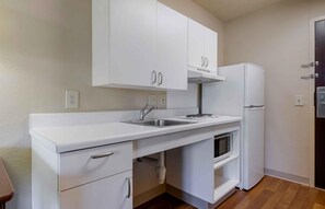 A compact kitchen with white cabinets, a stainless steel sink, a built-in oven, and a refrigerator. - Extended Stay America Suites Orlando Lake Mary 1036 Greenwoo (Lake Mary)