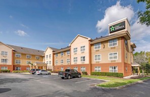 A hotel with multiple floors, a parking lot, and a sign indicating it's part of the Extended Stay America chain. - Extended Stay America Suites Orlando Lake Mary 1036 Greenwoo (Lake Mary)