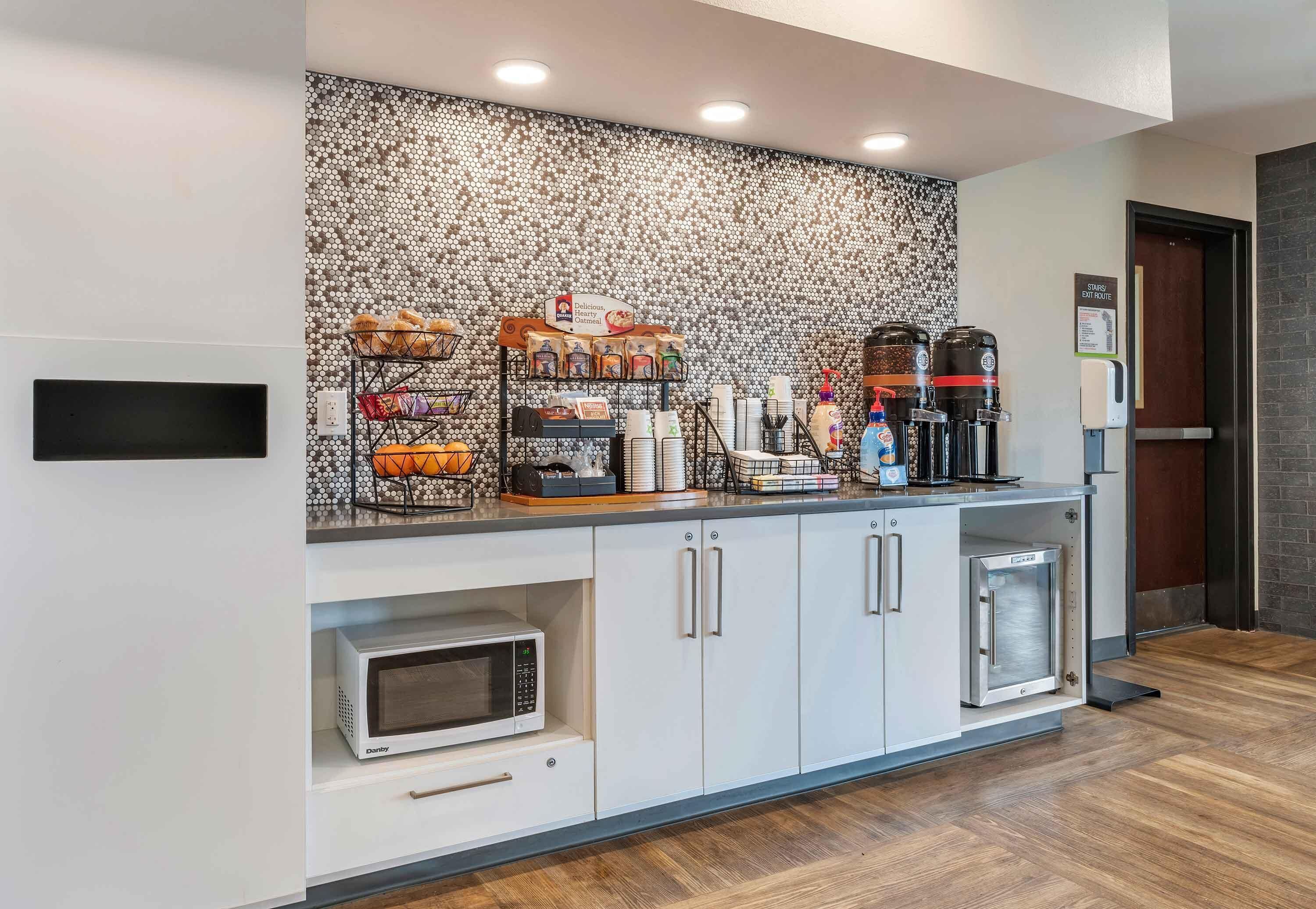 A modern kitchen with a tiled backsplash, a coffee station, and built-in appliances.