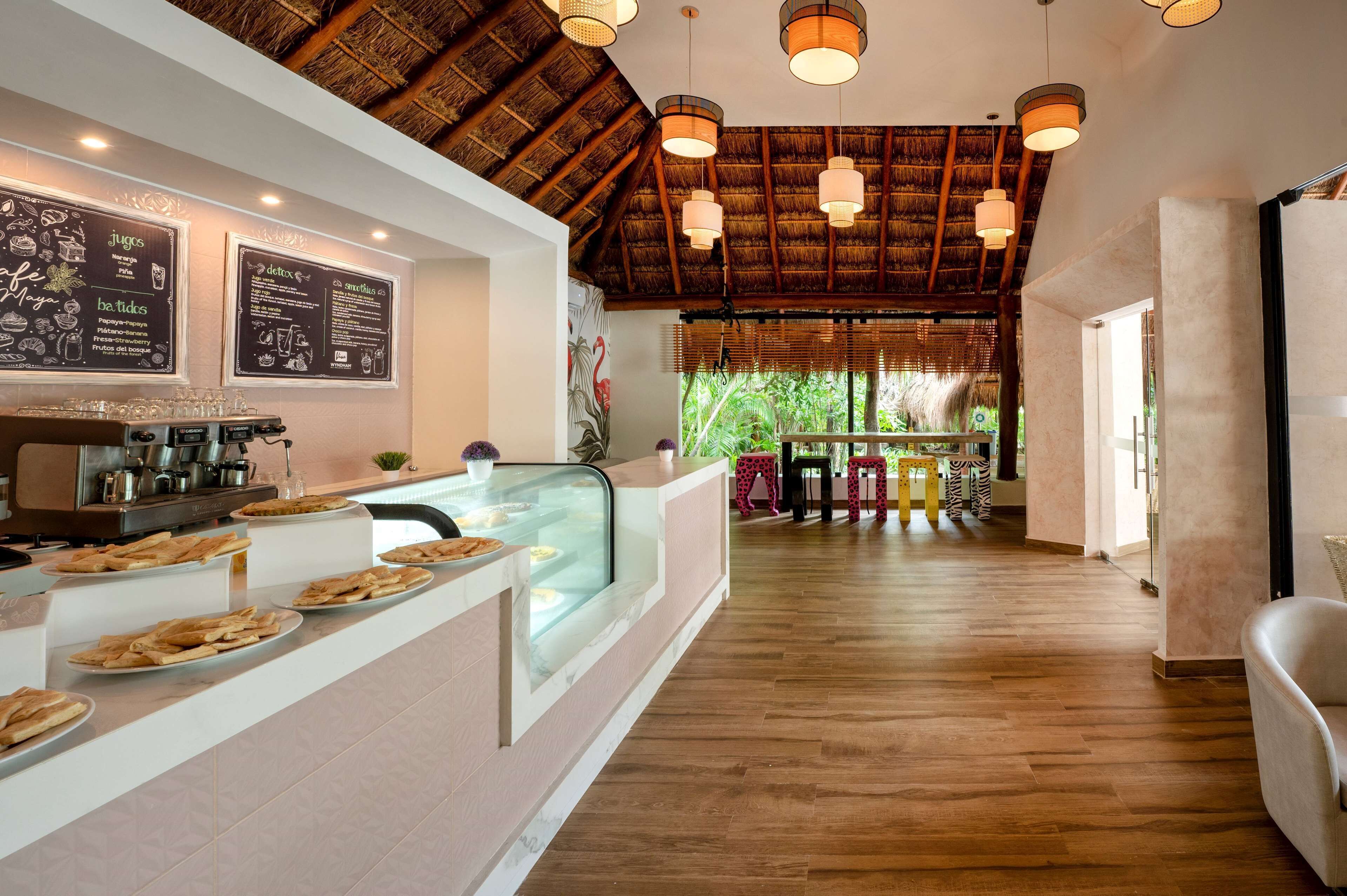 Un restaurant avec un plafond en bois, un comptoir où sont exposés des plats, et un tableau affichant le menu.