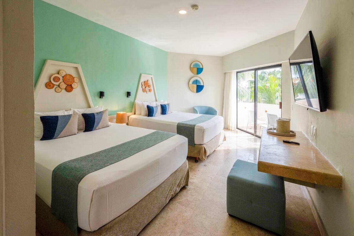 Habitación de hotel con dos camas, un escritorio y un televisor.