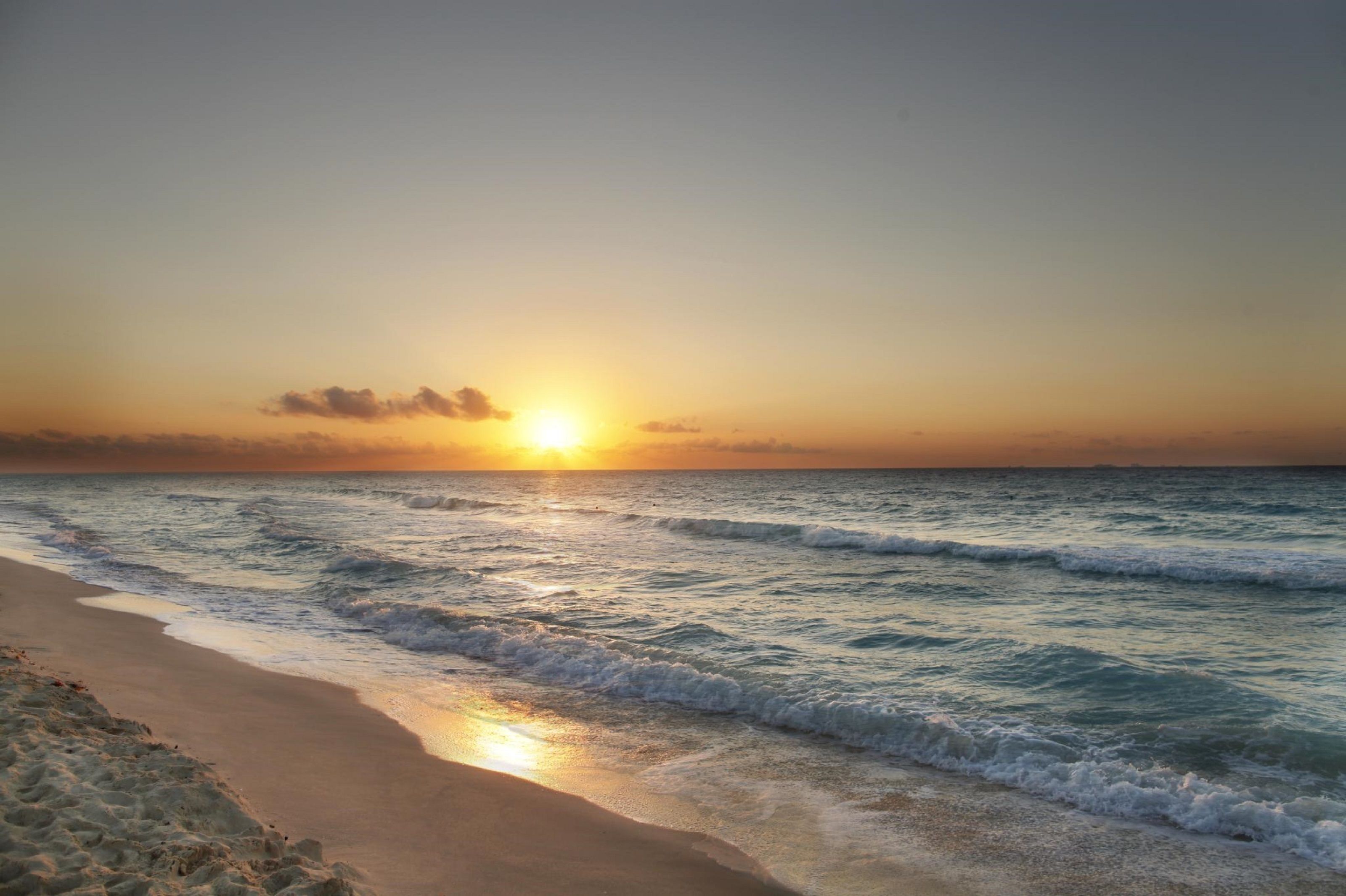 Une plage avec des vagues au coucher du soleil.