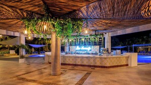 An outdoor bar area with a pool, lounge chairs, and hanging plants. - Viva Maya by Wyndham, A Trademark Resort (Playa del Carmen)