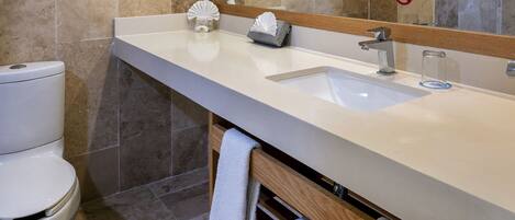 Un baño moderno con un revestimiento de baldosas color beige, un lavamanos blanco y un espejo sobre él.