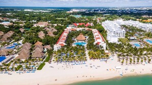Eine Luftaufnahme eines Resorts mit mehreren Gebäuden, einem Strand und einem Poolbereich.