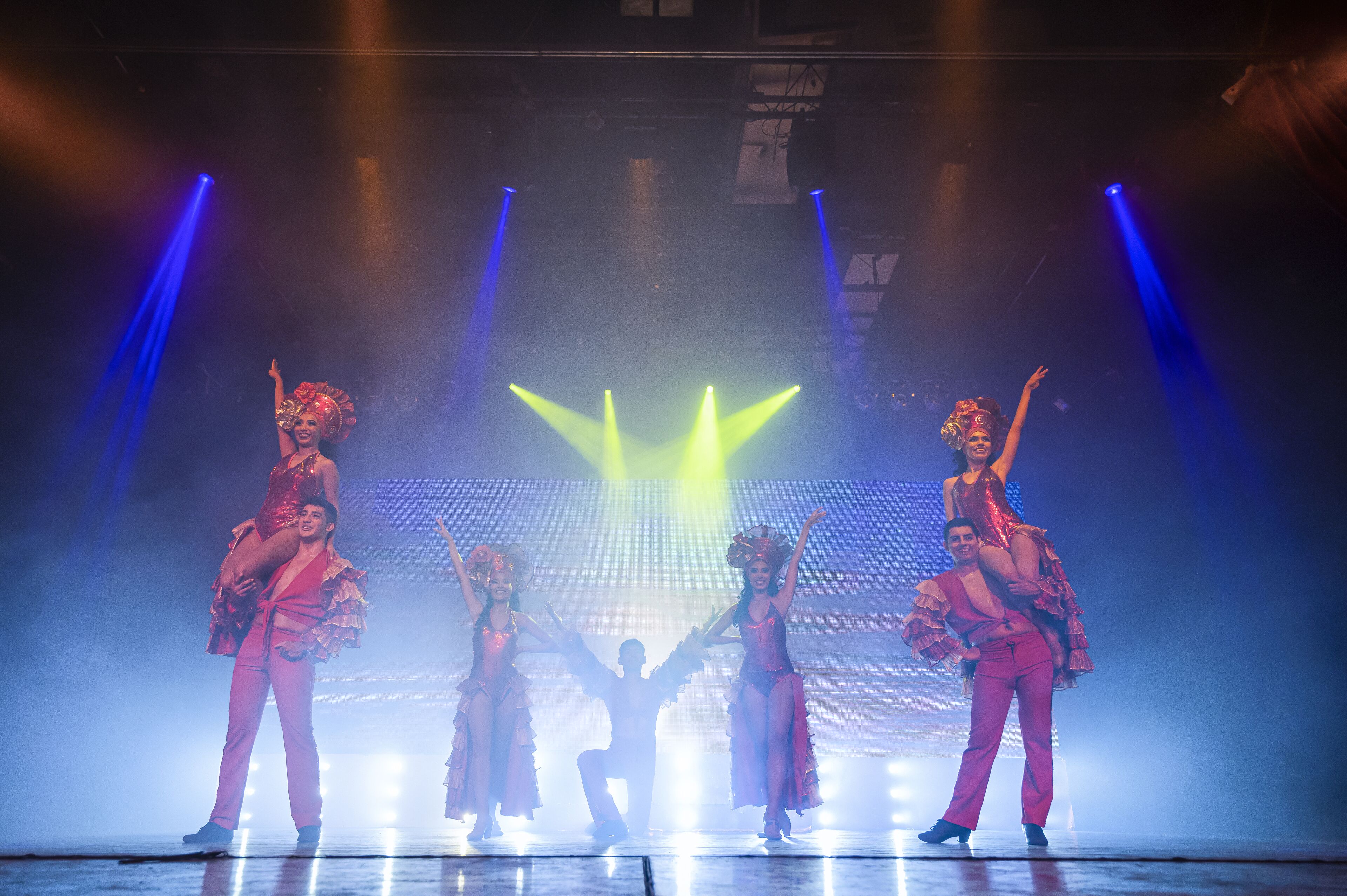 A stage with performers in matching costumes, a spotlight, and stage lighting.