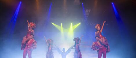 A stage with performers in matching costumes, a spotlight, and stage lighting.