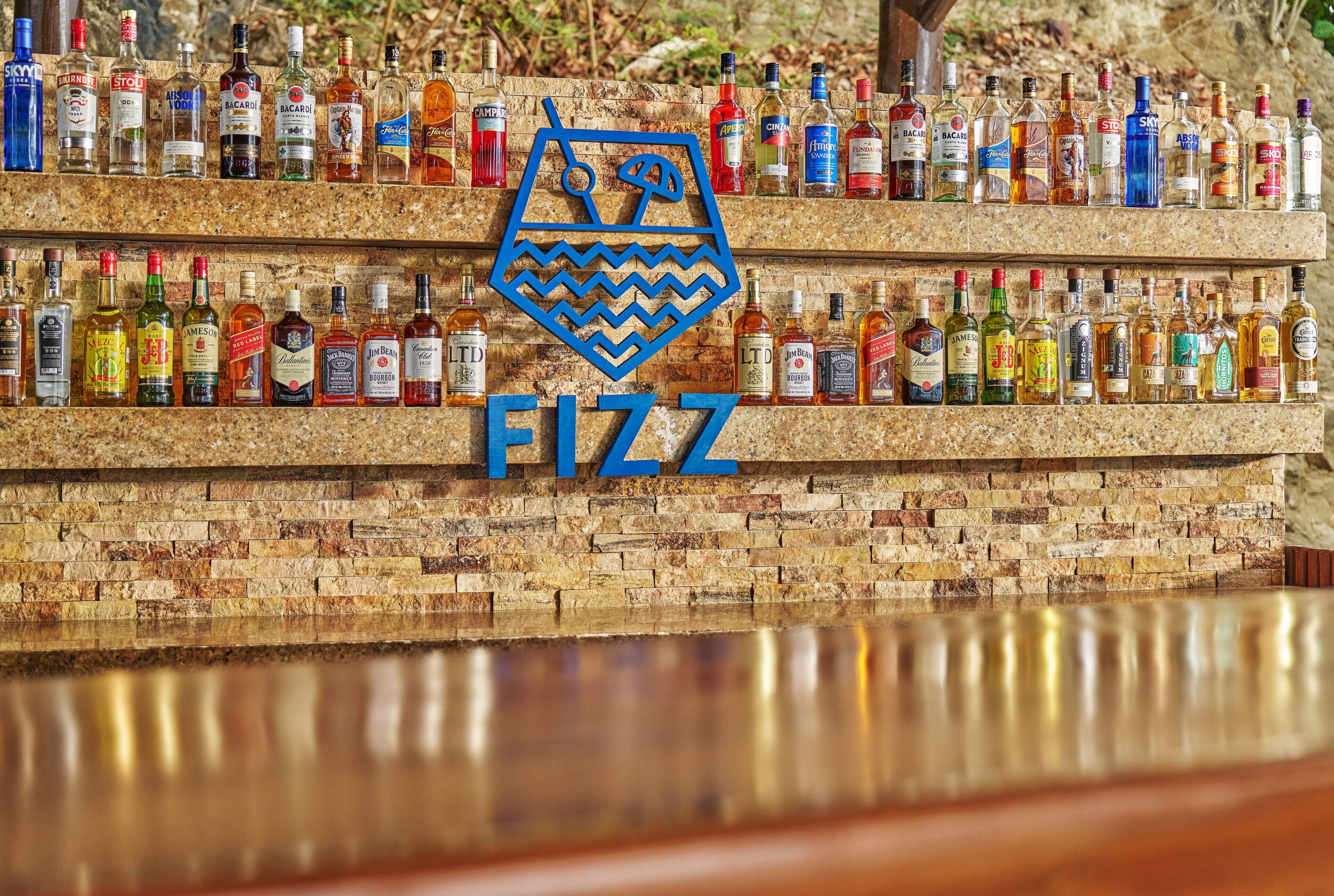 Un bar con diversas botellas de licor exhibidas en estantes frente a una pared de ladrillo.