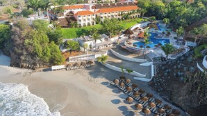 A resort with a beach, a pool area, and a building with multiple balconies.