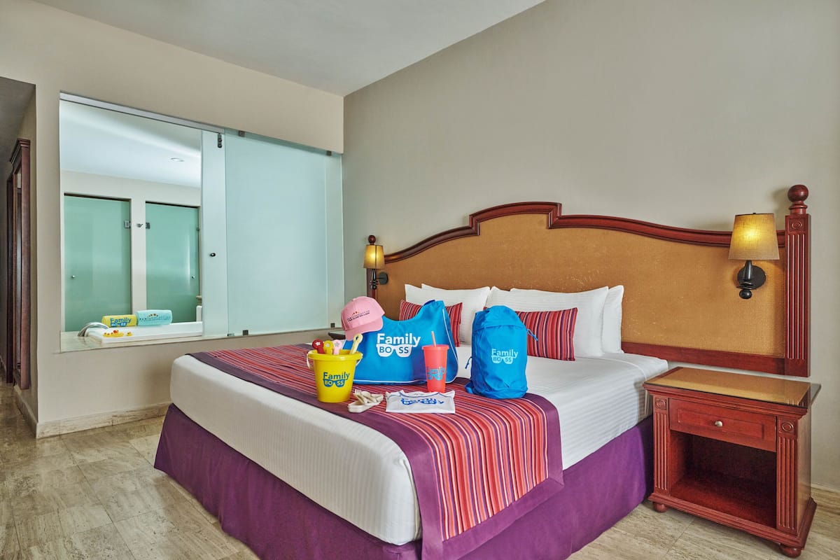 A hotel room with a bed, a nightstand, a window with a view, and a bathroom door.