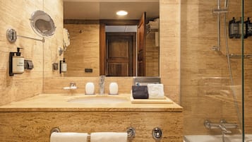 Un baño con tocador de mármol, un espejo grande, lavabo y cabina de ducha.