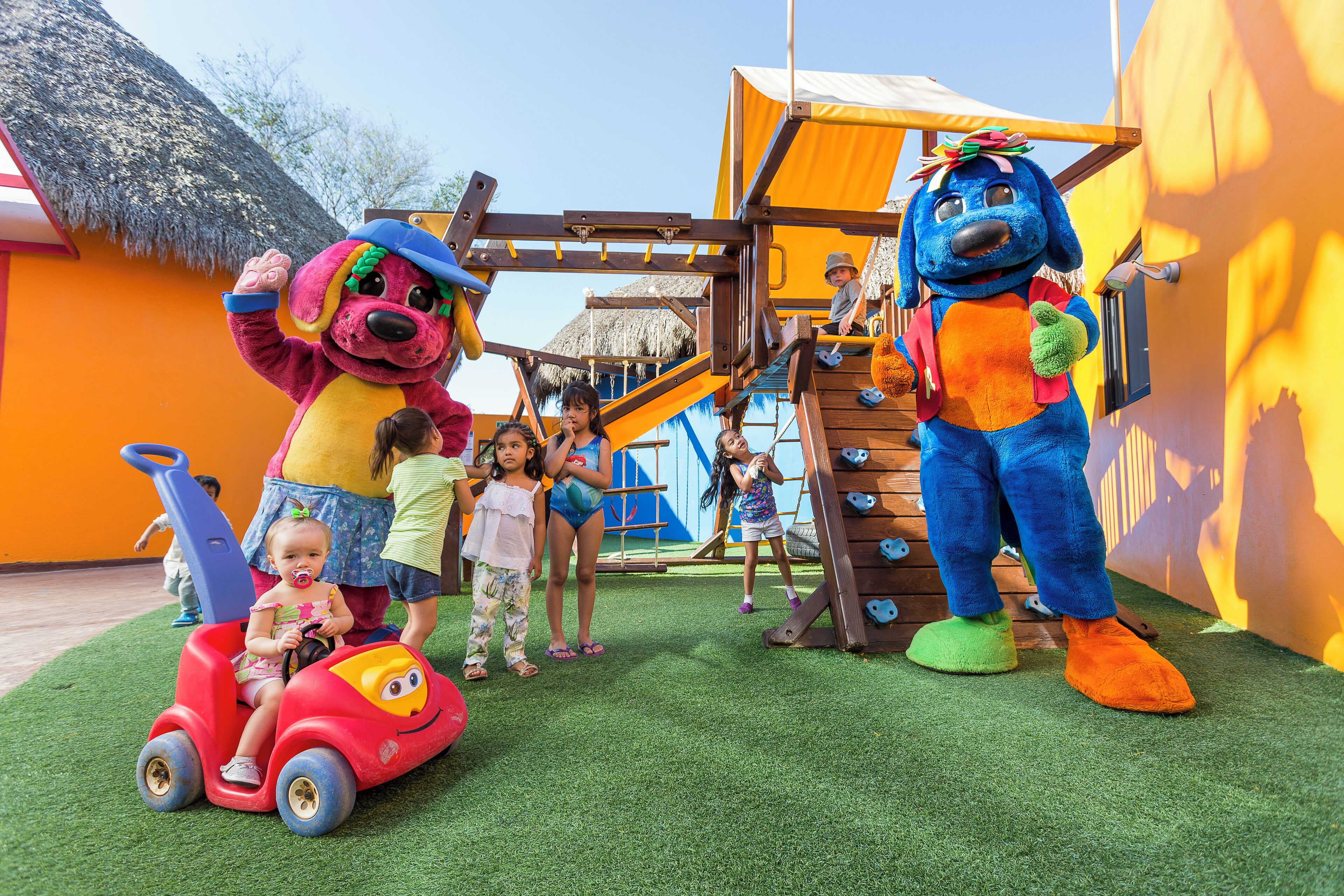 A children's play area with a slide, climbing structures, and a mascot.