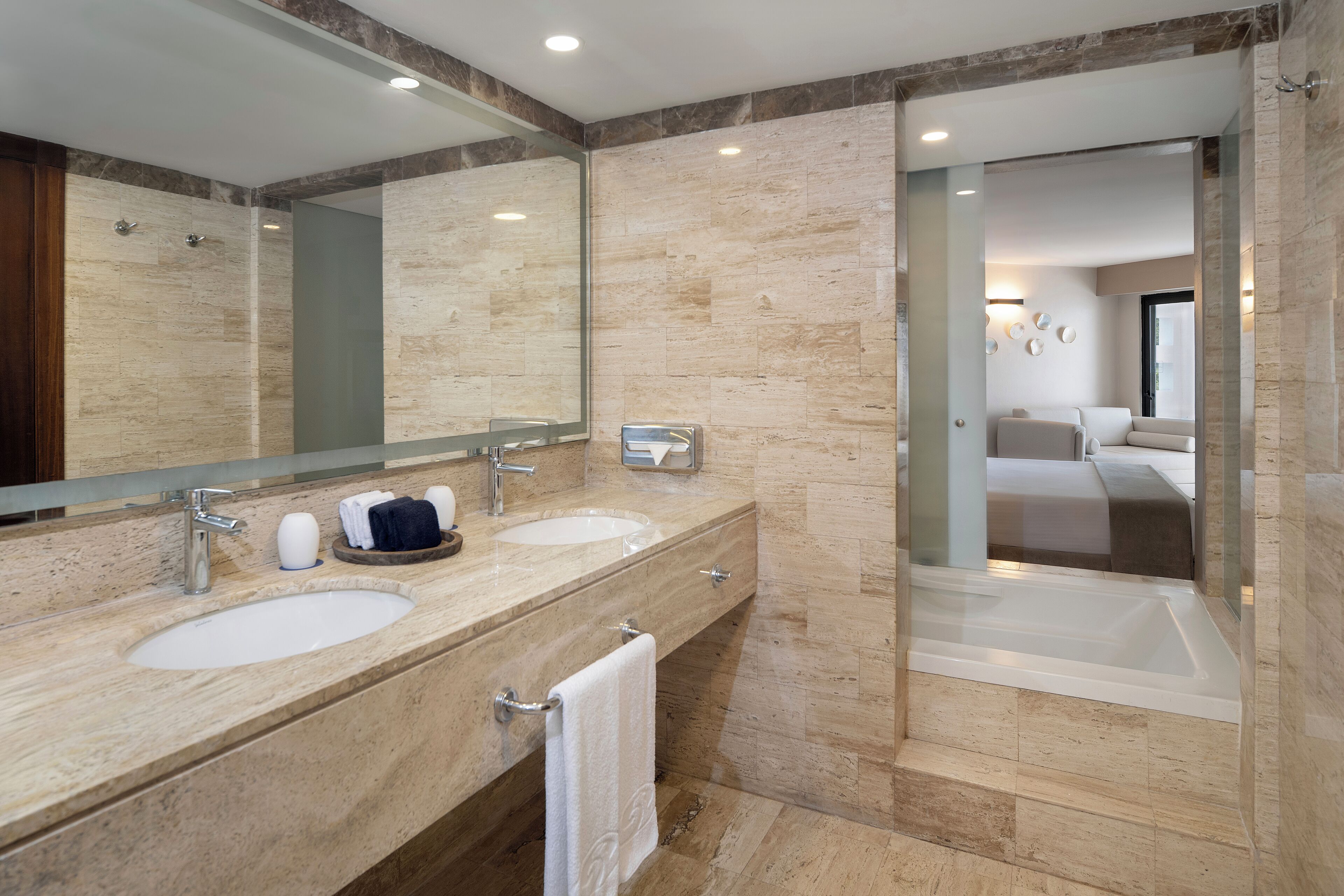 A modern bathroom with two sinks, a large mirror, and a glass-enclosed shower area.