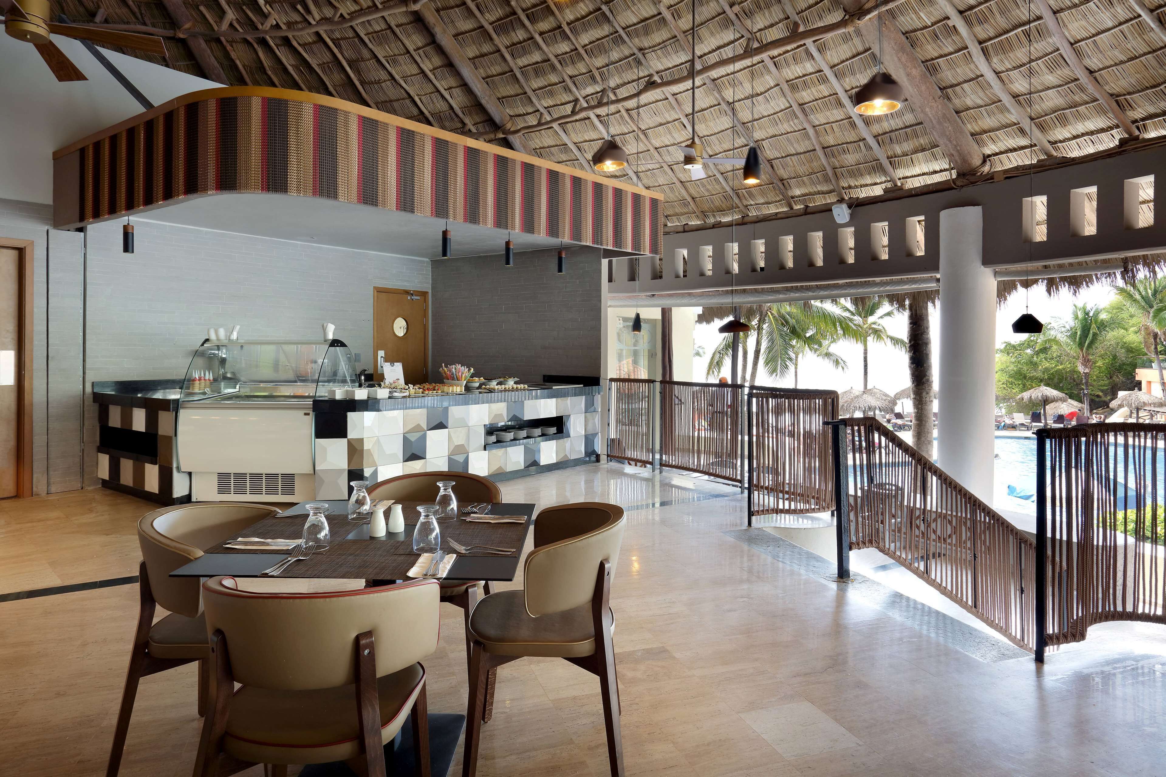 A restaurant with a high ceiling, a bar area, and a seating arrangement with tables and chairs.