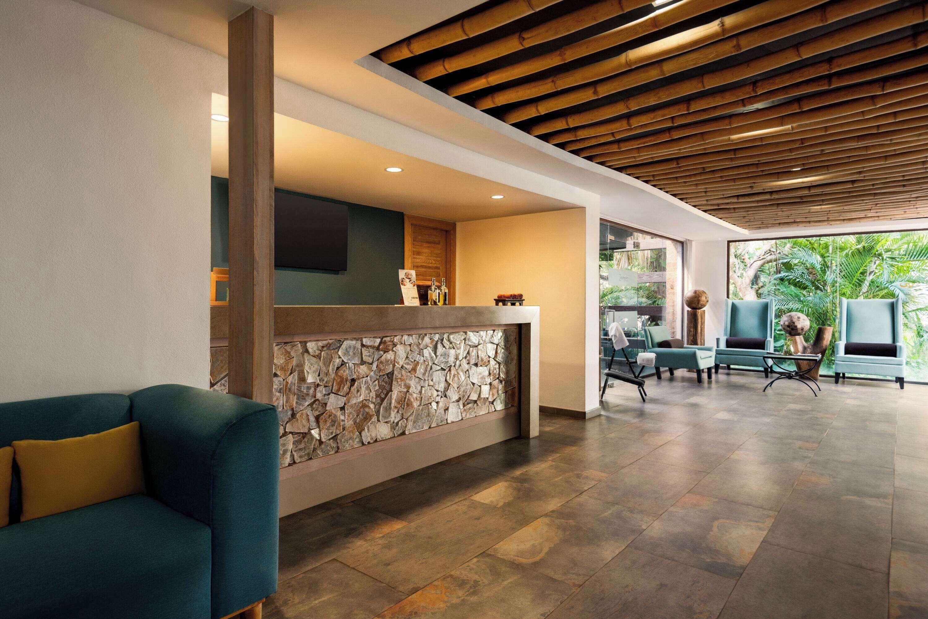 A reception area with a stone wall, a wooden ceiling, and a seating area with chairs and a sofa.