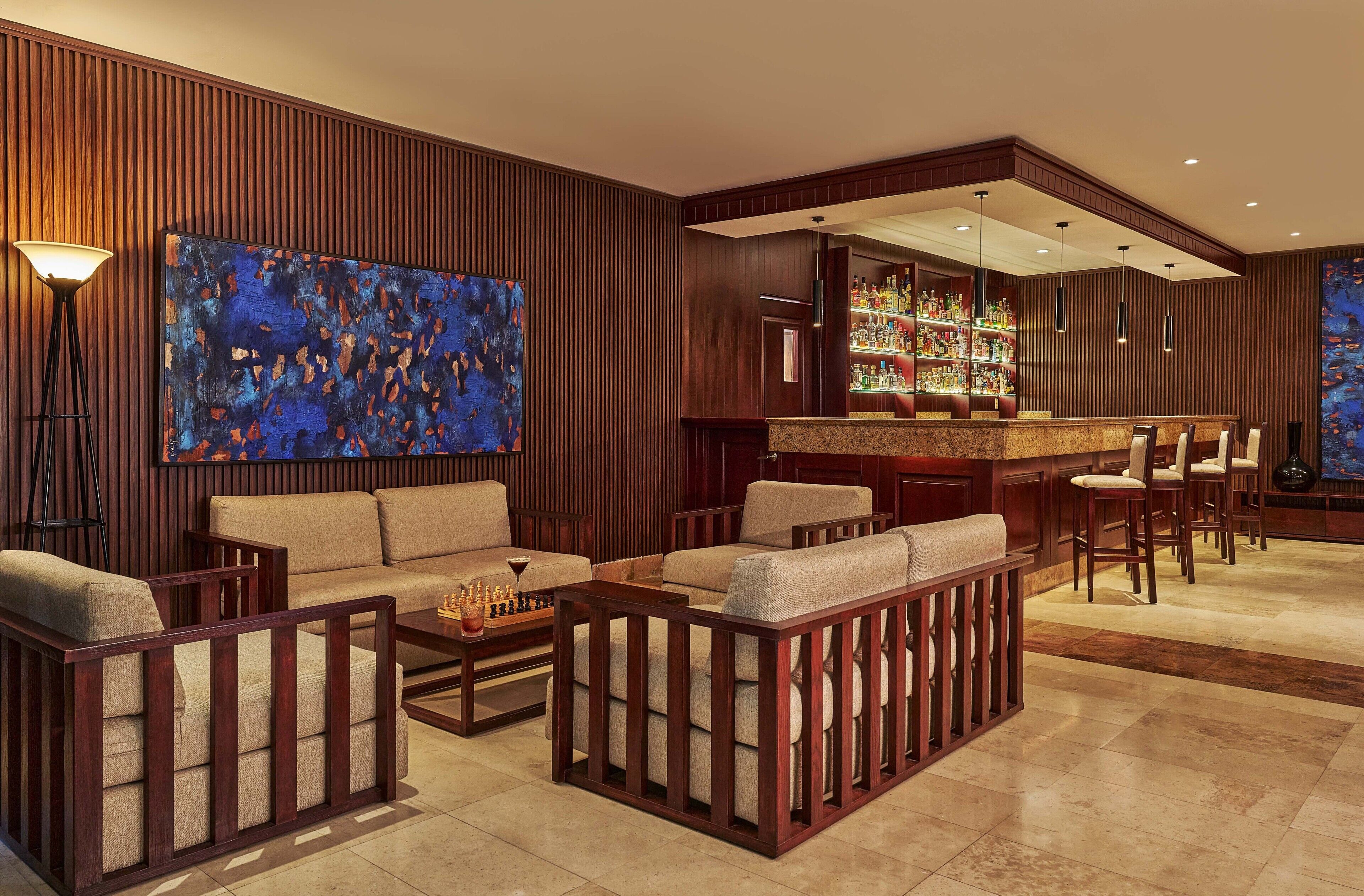 Un espace lounge moderne avec des panneaux de bois, un bar doté d’une vitrine et des sièges confortables.
