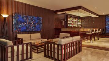Un espace lounge moderne avec des panneaux de bois, un bar doté d’une vitrine et des sièges confortables.