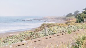 A wooden boardwalk leading to a beach with ocean views. - FogCatcher Inn (Cambria)