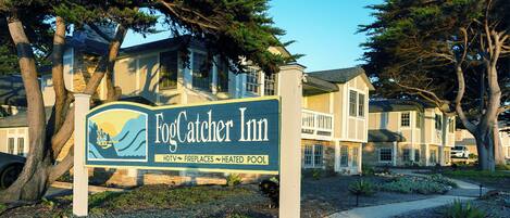 A sign for Fog Catcher Inn with a house in the background.