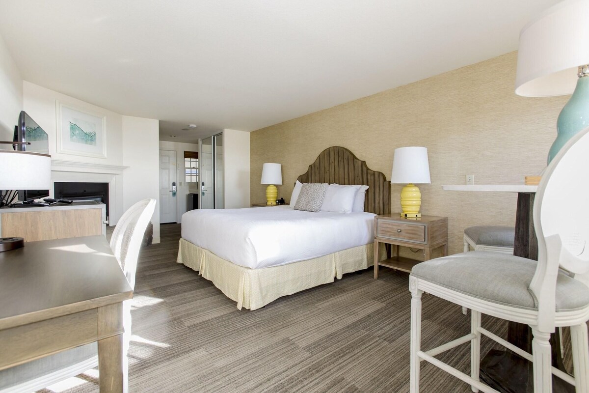 A hotel room with a bed, bedside tables, a desk, and a chair.