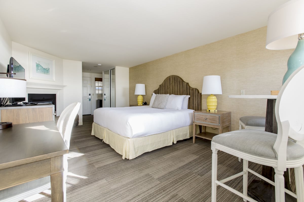 A hotel room with a bed, bedside tables, a desk, and a chair.