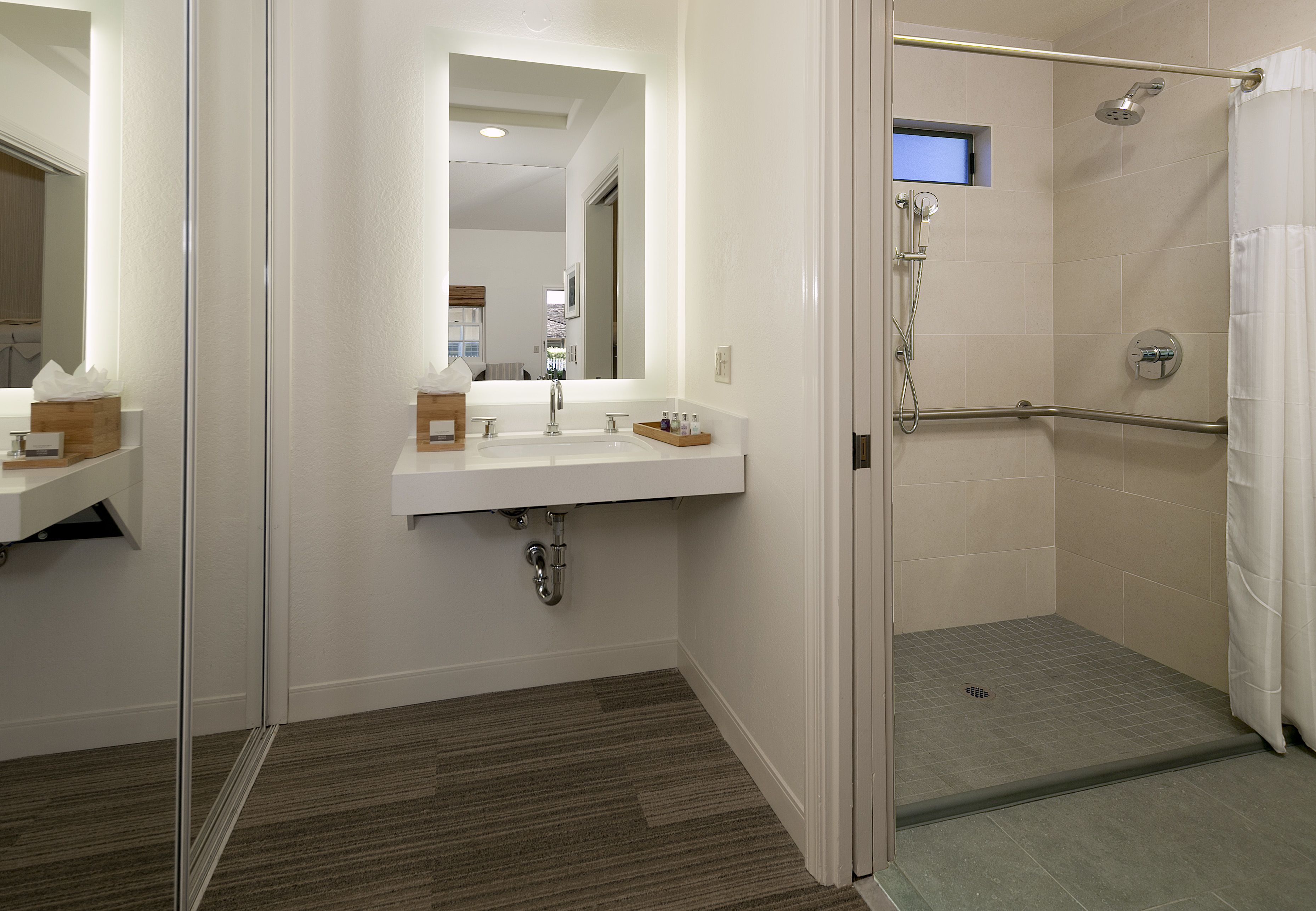 A modern bathroom with a white sink, mirror, and shower area.