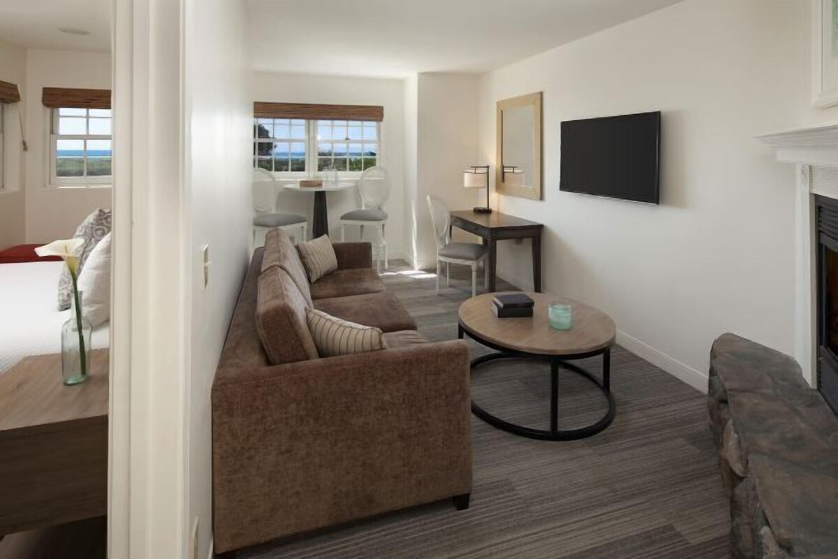 A modern living room with a sofa, a round coffee table, and a flat-screen TV mounted on the wall.