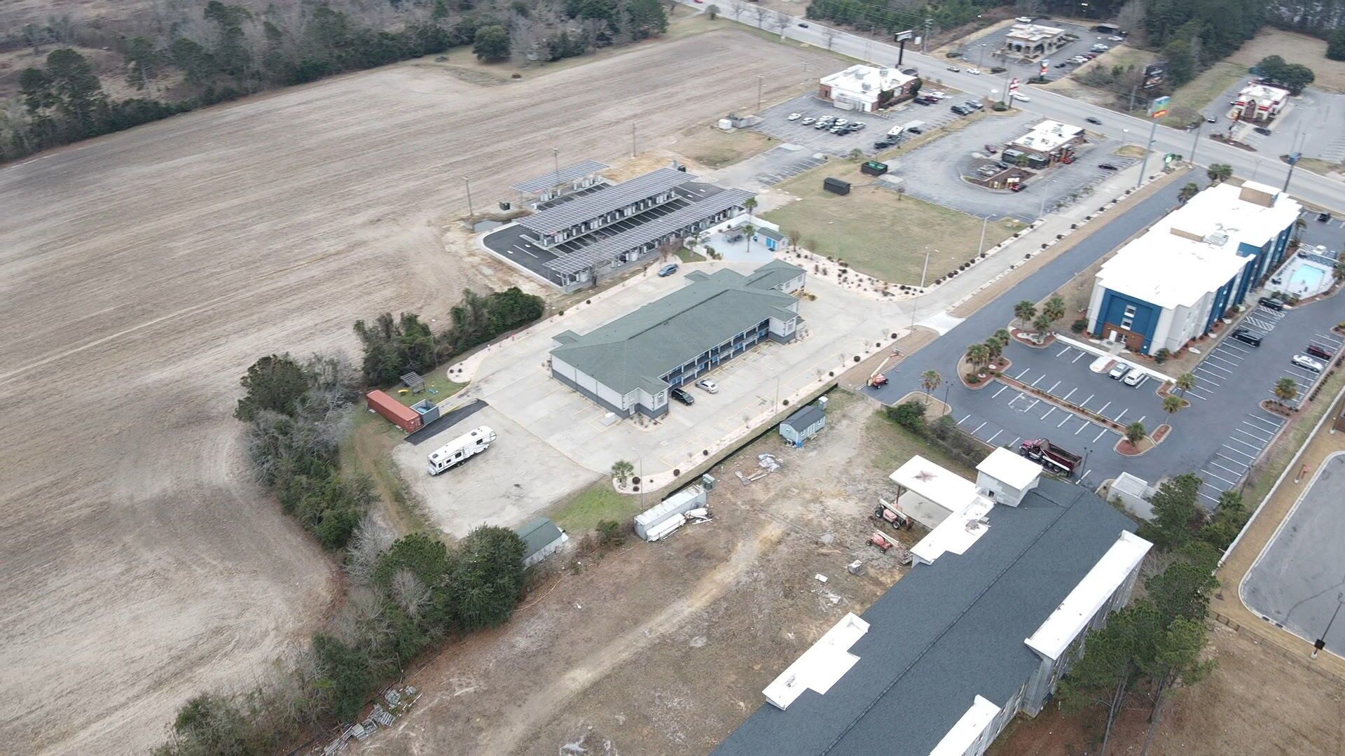 An industrial area with a large warehouse, parking lots, and a few smaller buildings.