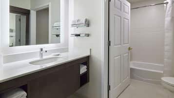 A bathroom with a white sink, mirror, and a bathtub.