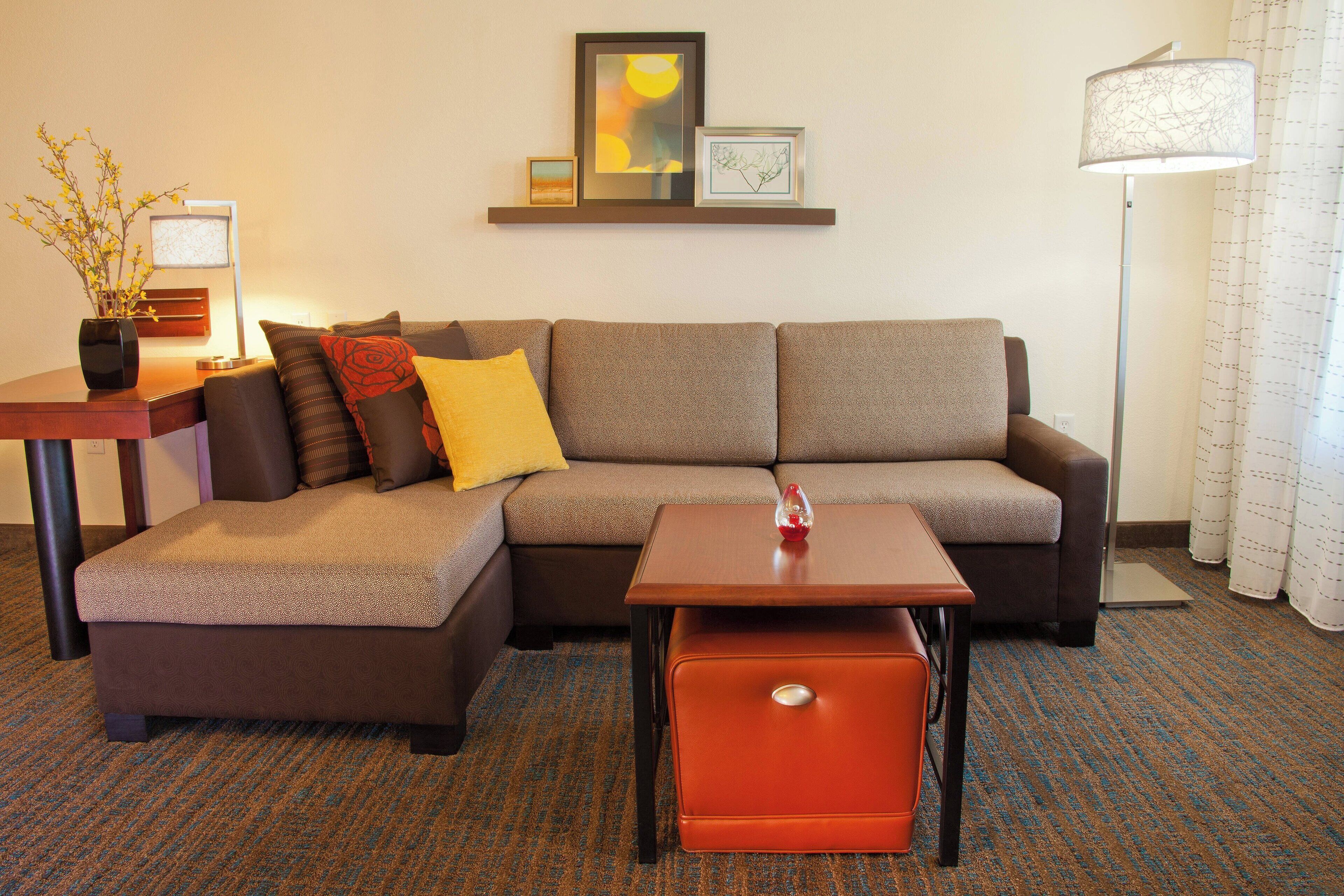 A modern living room with a sectional sofa, a small table, and a floor lamp.