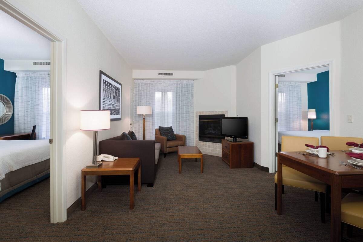 Une chambre d’hôtel comprenant un lit, un canapé, une télévision, un bureau et un coin repas.