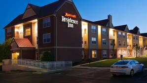 A Marriott Residence Inn building with a brick facade, multiple windows, and a parking lot with a white car. - Residence Inn by Marriott Olathe Kansas City (Olathe)