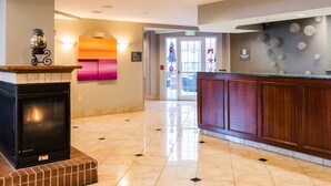 A lobby with a fireplace, a reception desk, and a wall with decorative elements. - Residence Inn by Marriott Olathe Kansas City (Olathe)