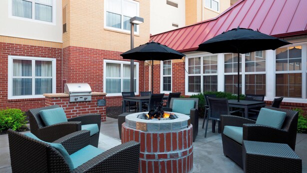 An outdoor patio area with wicker furniture, a fire pit, and a grill. - Residence Inn by Marriott Olathe Kansas City (Olathe)