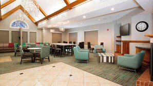 A hotel lobby with a dining area, seating arrangements, a fireplace, and a clock on the wall. - Residence Inn by Marriott Olathe Kansas City (Olathe)