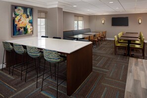 A conference room with a large table, multiple chairs, a sofa, and a television screen. - Residence Inn by Marriott Tysons (Vienna)