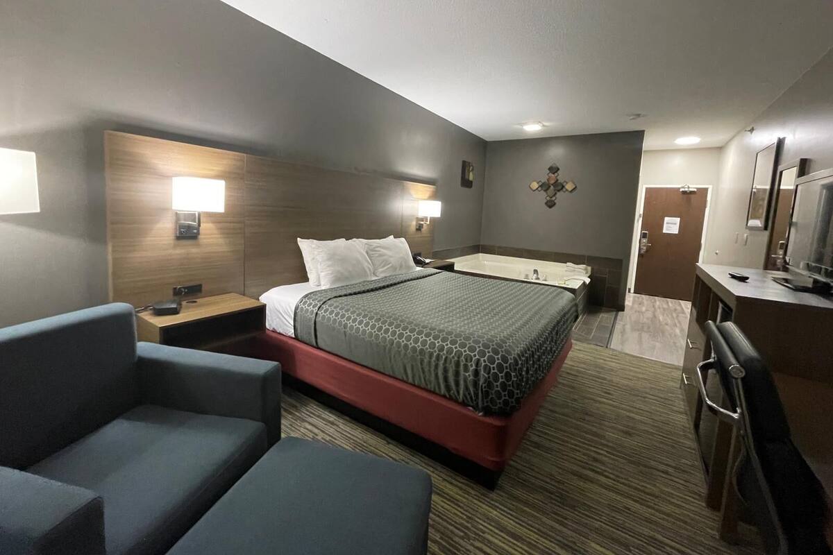 Habitación de hotel con una cama grande, un escritorio con silla, un televisor y un baño con bañera.
