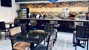 A breakfast corner with a stone backsplash, a Baymont sign, a refrigerator, and a coffee station. - Baymont by Wyndham Anderson (Anderson)