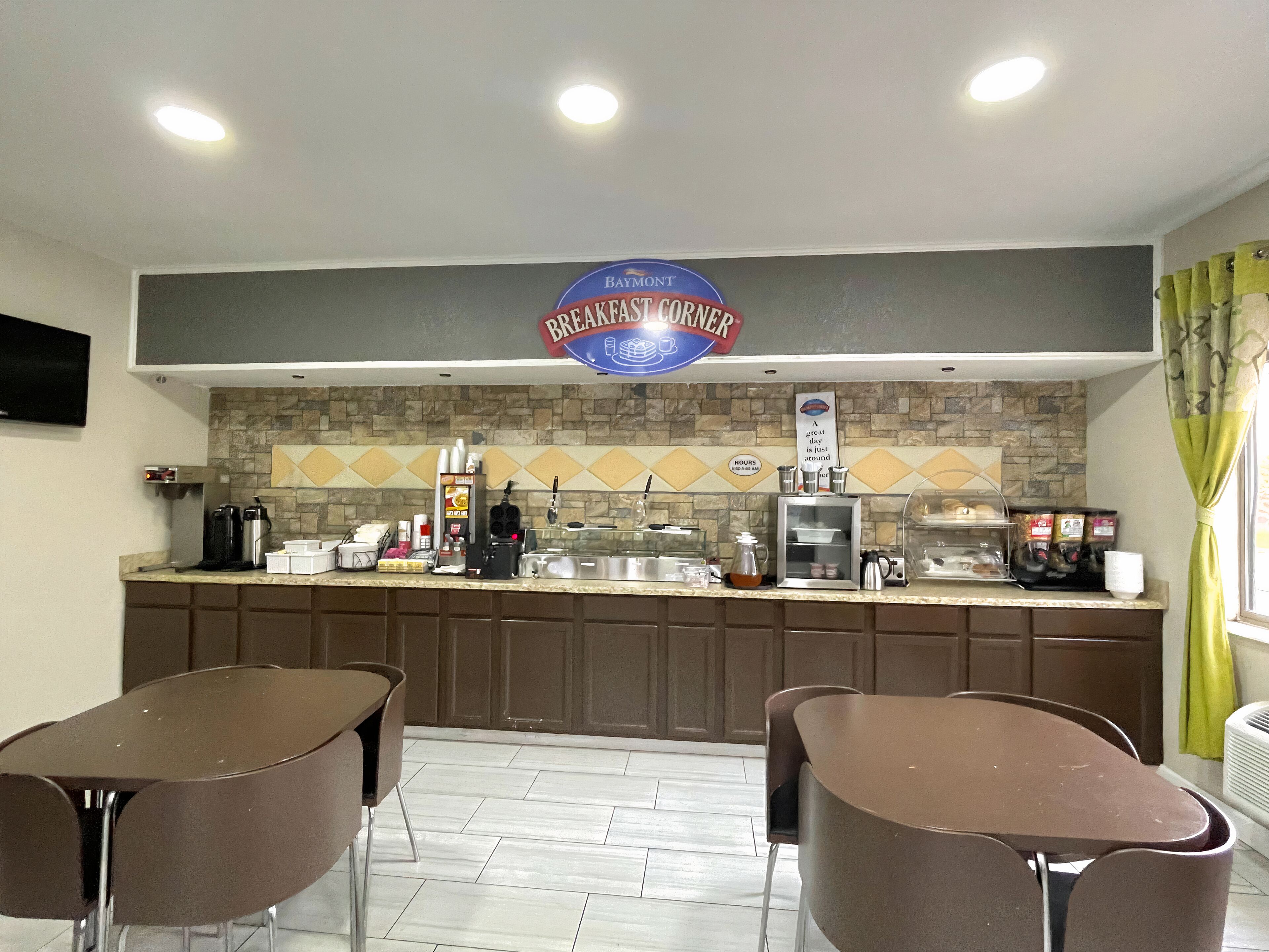A breakfast corner with a sign, coffee machines, and a counter.