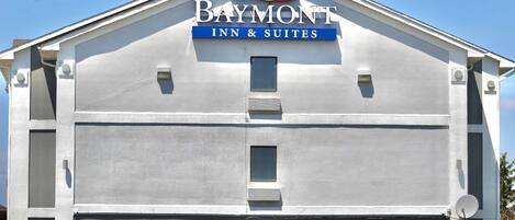 Edifício do Baymont Inn & Suites com design moderno e simples, apresentando uma placa grande na parte superior.