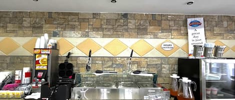 A breakfast corner with a sign, a coffee machine, a kettle, and a menu board.
