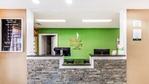 Un comptoir d’accueil doté d’un mur vert et d’un socle en marbre, sur lequel est apposée une enseigne indiquant « Quality Inn ».